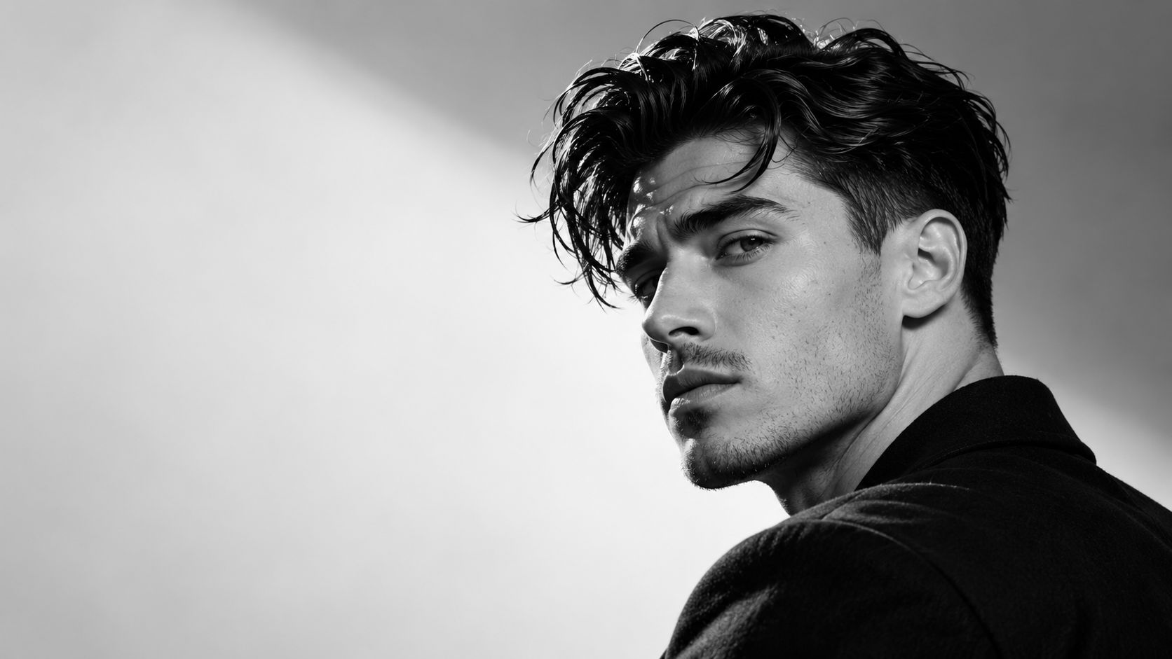 Man with a textured, swept-back cut and tapered sides, photographed in black and white